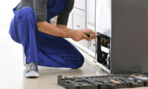 un tecnico in ginocchio controlla la parte sotto di un forno